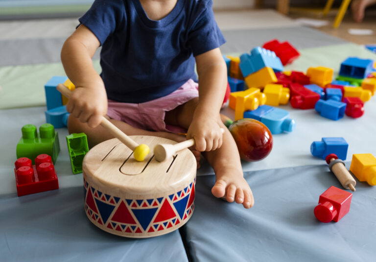 Little boy having fun and playing wooden toy drum